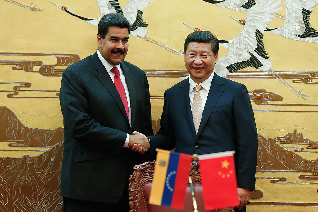El líder chino, Xi Jinping (derecha), y el presidente venezolano, Nicolás Maduro (izquierda), se dan la mano durante una ceremonia de firma entre ambos países en el Gran Salón del Pueblo de Beijing, el 22 de septiembre de 2013. (LINTAO ZHANG/AFP a través de Getty Images).