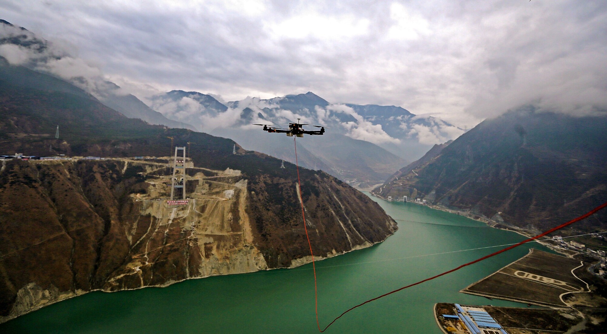 Un vehículo aéreo no tripulado (UAV) que remolca un cable sobrevuela el río Dadu en Ya'an, provincia de Sichuan, China, el 20 de diciembre de 2016. El UAV se utiliza para tensar un cable que conecta los dos extremos de un puente durante su construcción. (Zhang Jian/Chengdu Economic Daily/VCG).