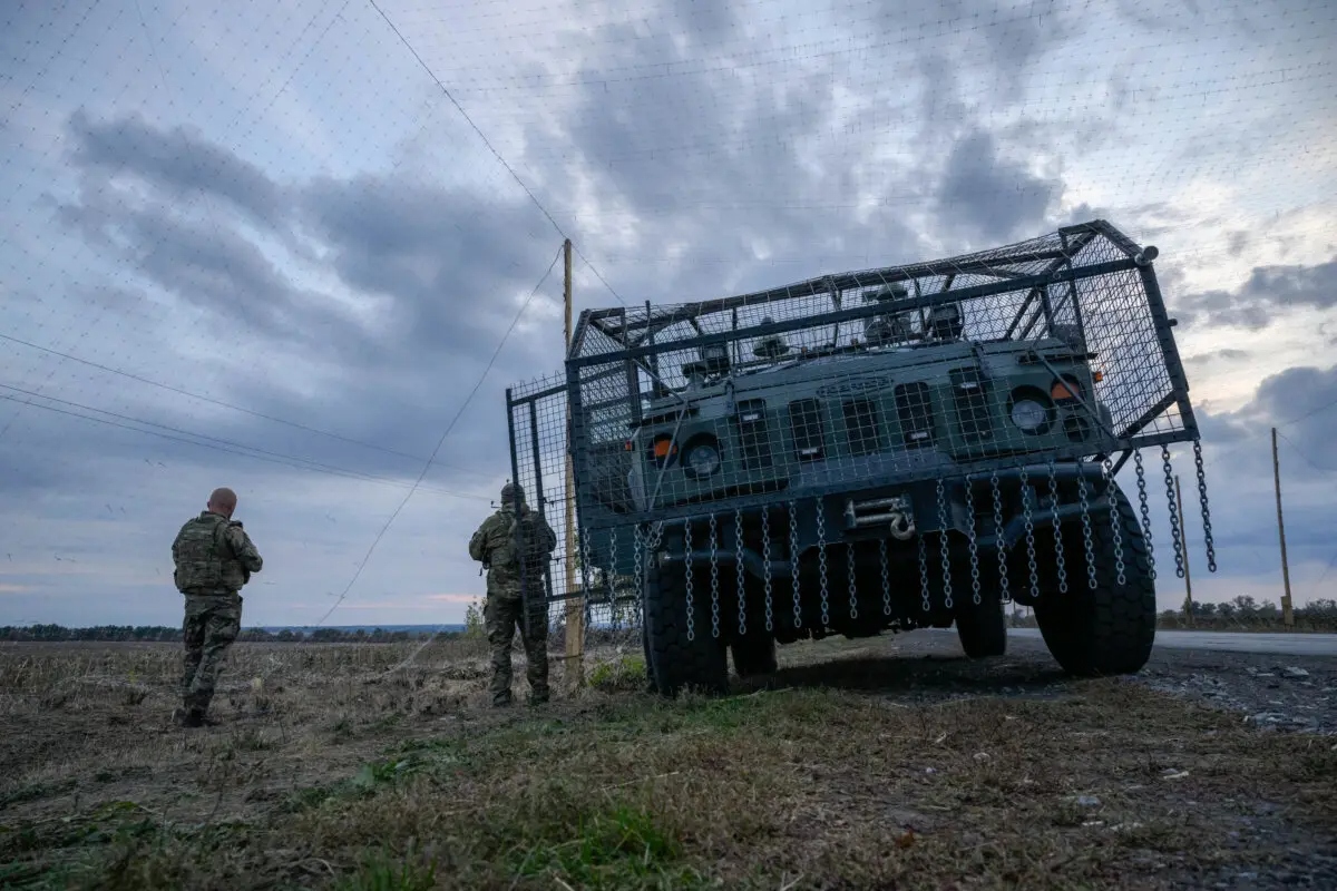 Soldados ucranianos junto a un vehículo militar blindado rodeado por una jaula para protegerse de los ataques con drones en una carretera cerca de Oleksandrivka, Ucrania, el 6 de octubre de 2025. (Ed Jones/AFP vía Getty Images)