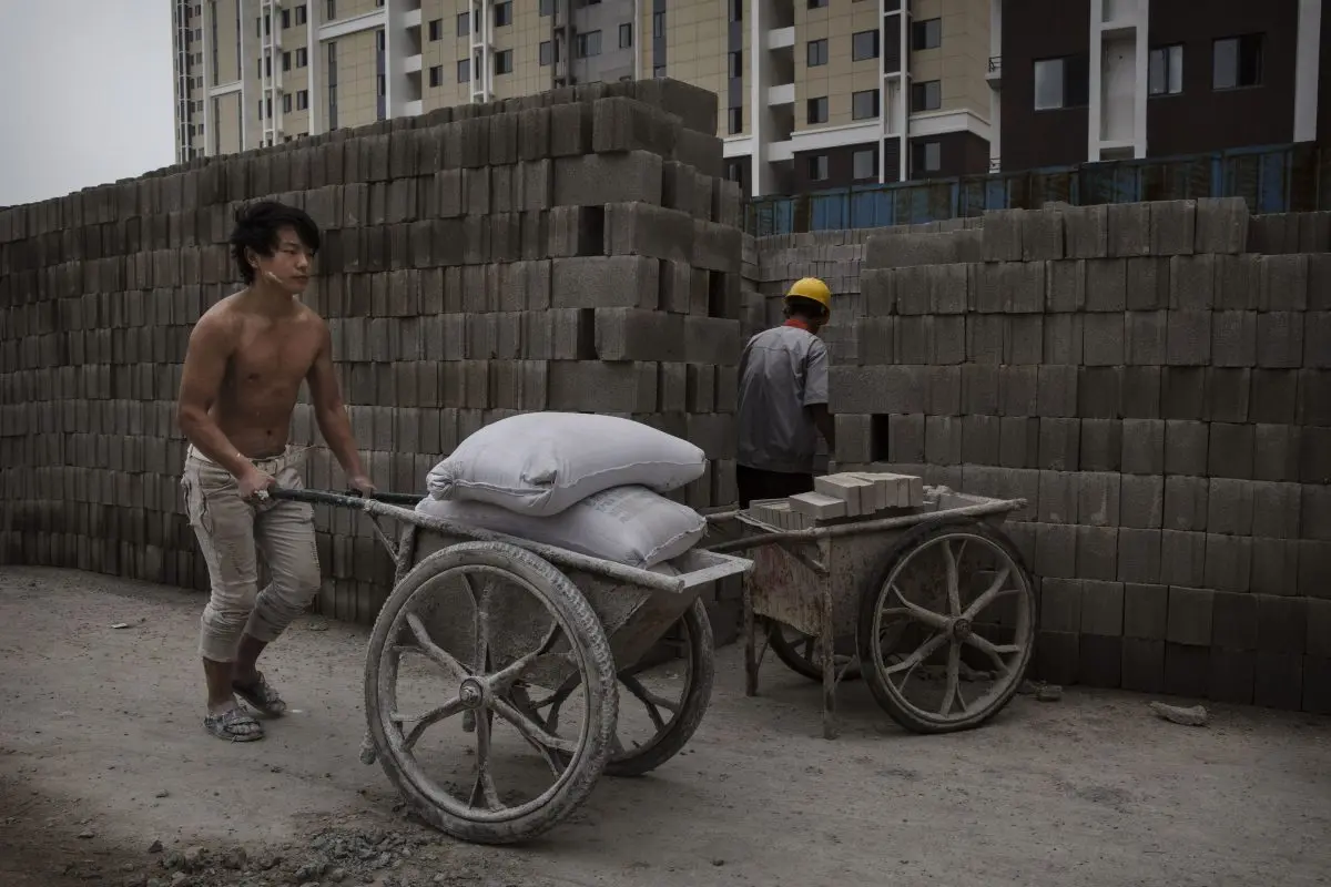 Un trabajador de la construcción chino empuja una carga de hormigón en la obra de un nuevo complejo de apartamentos en Beijing el 29 de agosto de 2014. (Kevin Frayer/Getty Images)