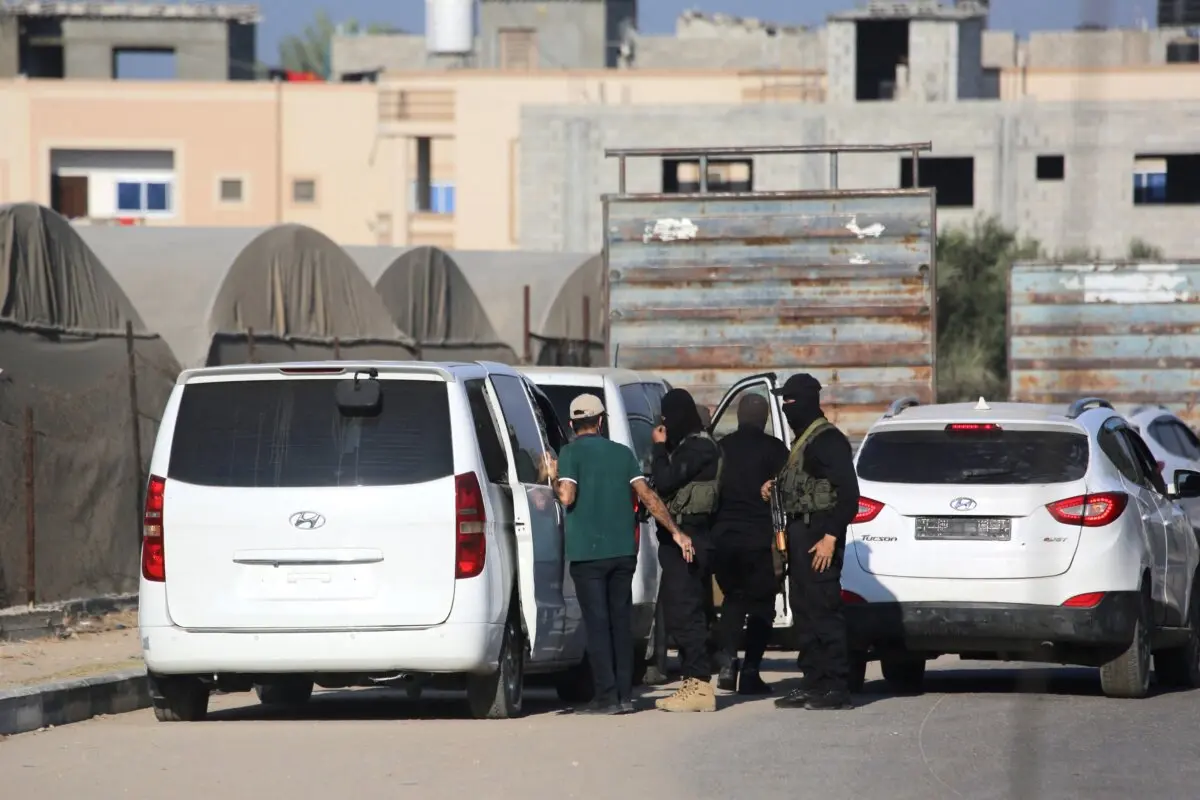 Miembros del ala militar de Hamás, las Brigadas Al-Qassam, montan guardia junto a los vehículos que transportan a los rehenes israelíes liberados en una carretera principal de Deir al-Balah, en el centro de la Franja de Gaza, el 13 de octubre de 2025. (Bashar Taleb/AFP a través de Getty Images)