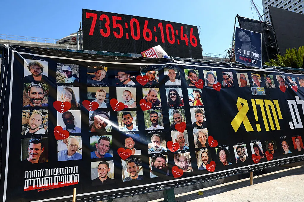<em>Retratados de rehenes israelíes retenidos por Hamás en la Franja de Gaza desde los ataques del 7 de octubre de 2023 se exhiben bajo un reloj digital que muestra los días, horas y minutos que han permanecido en cautiverio, frente al Museo de Arte de Tel Aviv, conocido como la "Plaza de los Rehenes", en Tel Aviv, Israel, el 11 de octubre de 2025. (Jack Guez/AFP vía Getty Images)</em>