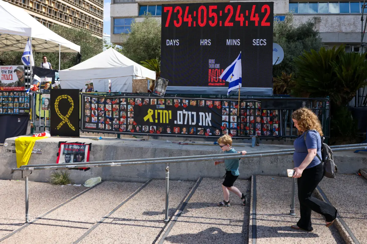 <em>Una mujer y un niño caminan junto a carteles de rehenes retenidos por Hamás en Gaza, en la Plaza de los Rehenes de Tel Aviv, el 10 de octubre de 2025. (Ahmad Gharabli/AFP vía Getty Images)</em>