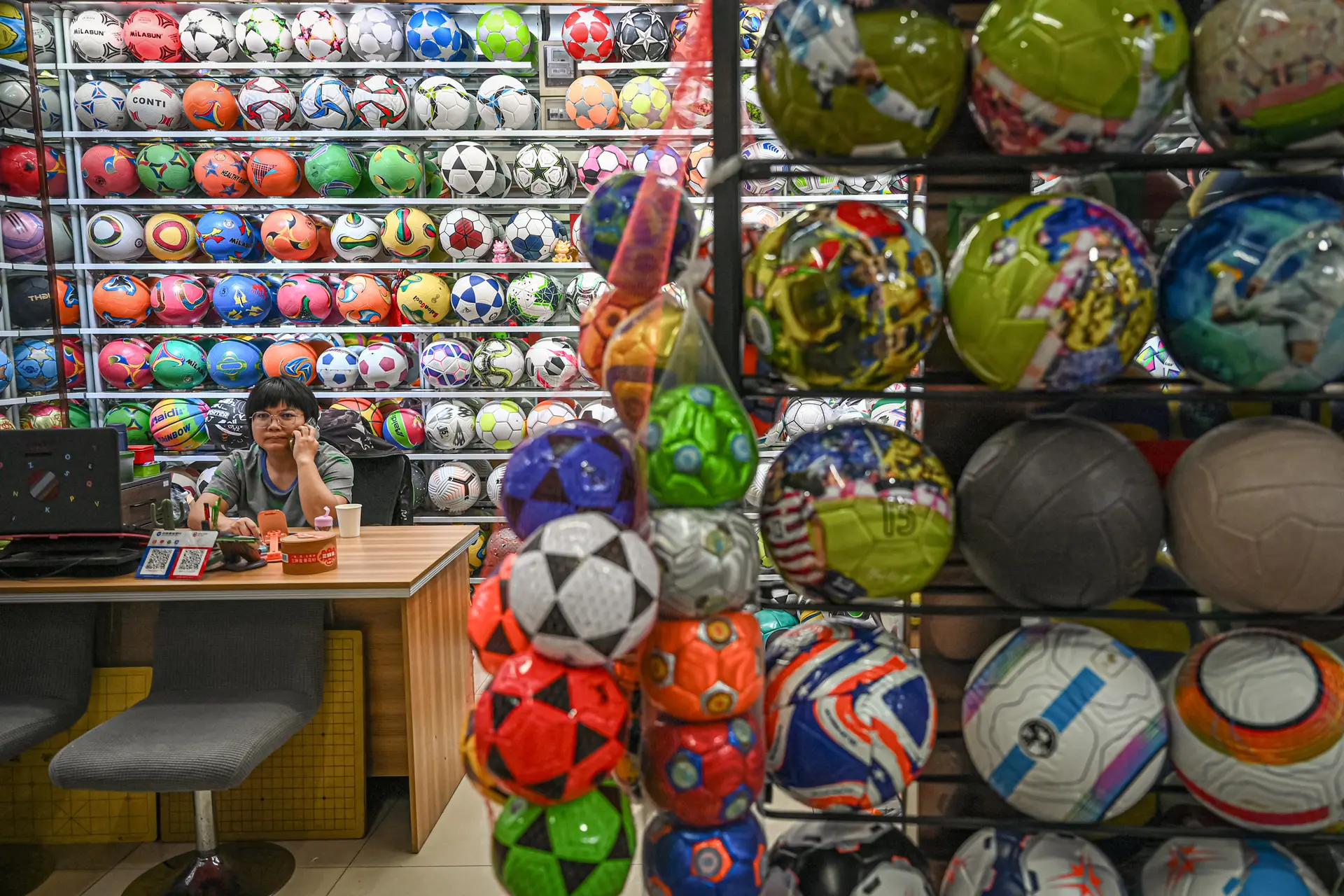 Un vendedor espera a los clientes en un puesto de artículos deportivos en un mercado comercial en Yiwu, provincia de Zhejiang, China, el 17 de septiembre de 2025. A medida que los países occidentales imponen aranceles a los productos chinos para frenar la inundación de sus mercados con productos baratos, el régimen chino se ha visto obligado a mirar hacia el mercado interno. (Jade Gao/AFP a través de Getty Images).