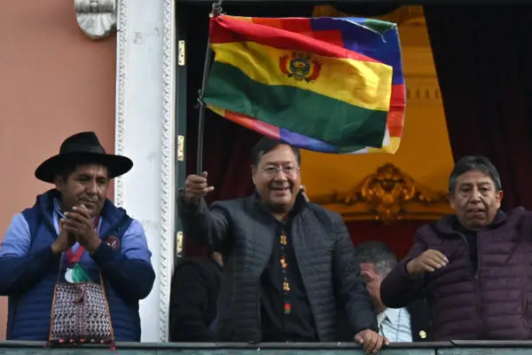 El presidente boliviano Luis Arce (C) ondea una bandera boliviana en el balcón del Palacio de gobierno en La Paz el 26 de junio de 2024. (Aizar Raldes/AFP).