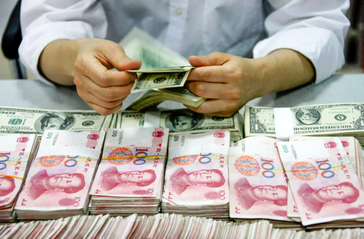 Billetes de dólar estadounidense contados junto a pilas de billetes de 100 yuanes (RMB) chinos en un banco de Huaibei, en la provincia de Anhui, al este de China, el 24 de septiembre de 2013. (STR/AFP vía Getty Images)