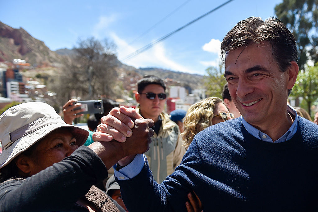 <em>El candidato presidencial de Bolivia por el Partido Demócrata Cristiano (PDC), Rodrigo Paz, saluda a un simpatizante al llegar a un centro de votación mientras acompaña a su hija Catalina (fuera de cuadro) a votar durante la segunda vuelta de las elecciones presidenciales en La Paz, el 19 de octubre de 2025. (JORGE BERNAL/AFP a través de Getty Images)</em>