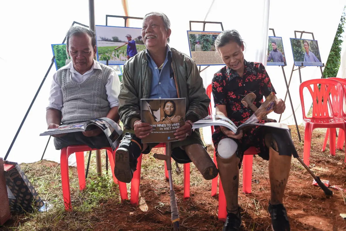 Víctimas de las minas terrestres Phan Van Ty (izquierda), Truong Uu (centro) y Hoang Thi Luu (derecha) leen libros sobre agricultores que fueron víctimas de las minas terrestres, el 6 de enero de 2020. (Nhac Nguyen/AFP vía Getty Images)