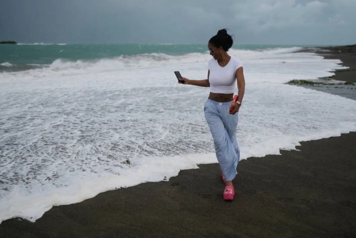 Una mujer pasea por la playa antes de la llegada prevista del huracán Melissa a Kingston, Jamaica, el 26 de octubre de 2025. (AP Photo/Matias Delacroix)