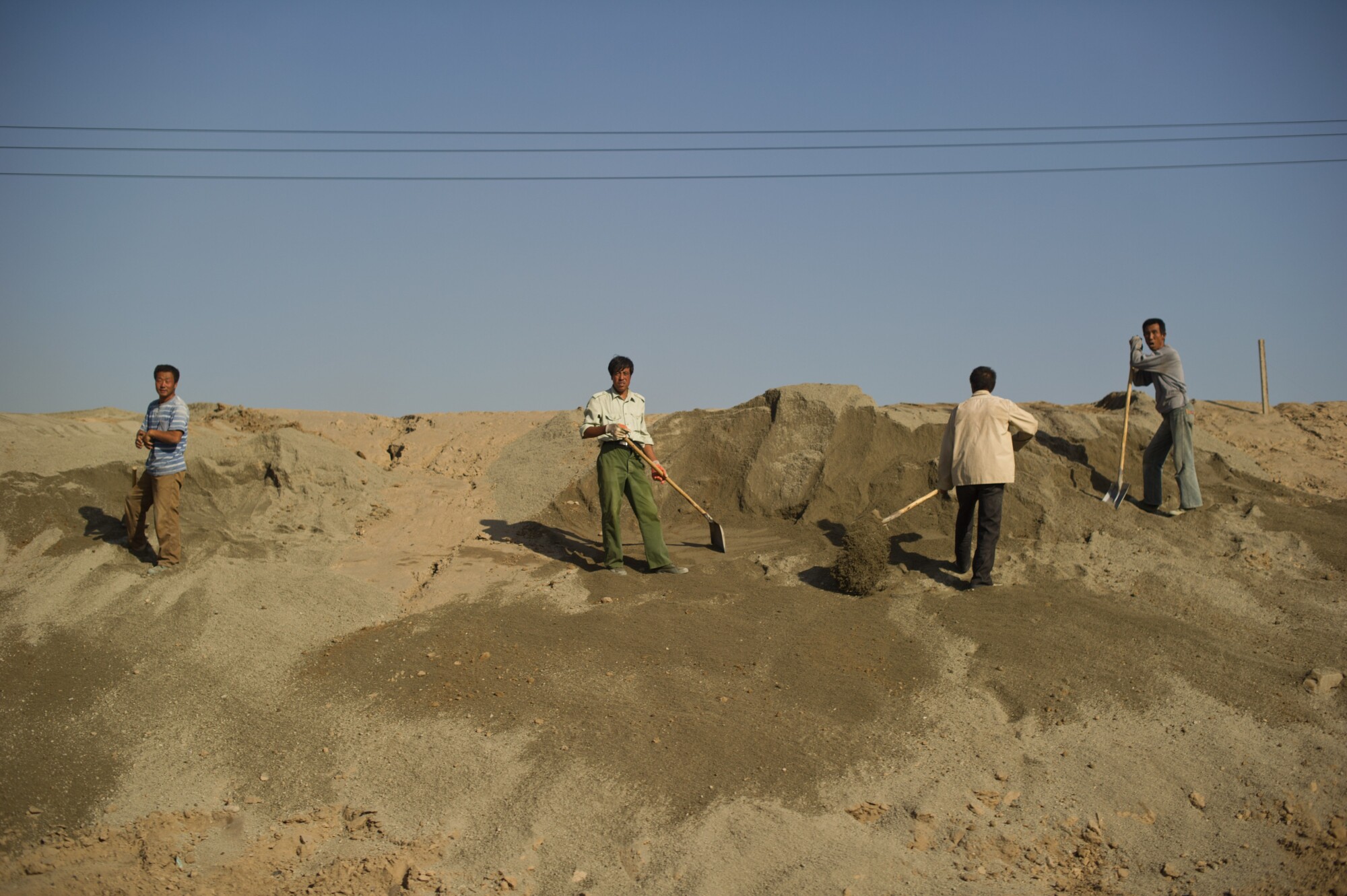 Trabajadores junto a una carretera cerca de un lago tóxico rodeado de refinerías de tierras raras cerca de Baotou, Mongolia, el 19 de agosto de 2012. (Ed Jones/AFP vía Getty Images).