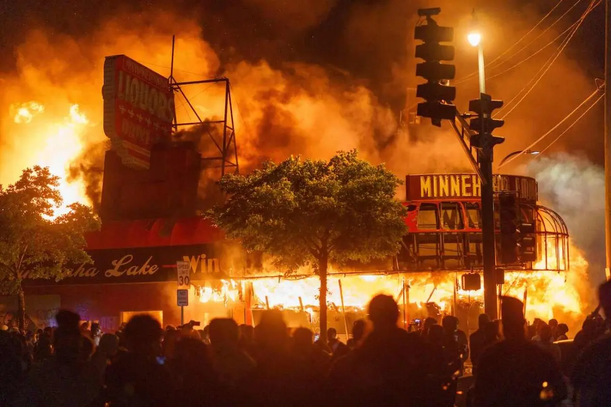 Manifestantes se reúnen frente a una licorería en llamas cerca de la tercera comisaría de policía de Minneapolis el 28 de mayo de 2020. (Kerem Yucel/AFP a través de Getty Images).