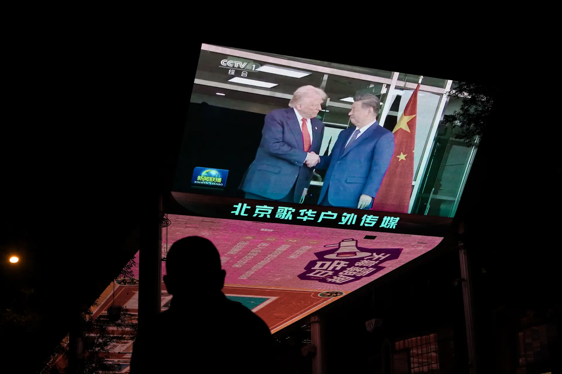 La cobertura informativa de la reunión entre el presidente estadounidense Donald J. Trump y el líder chino Xi Jinping en Corea del Sur se ve en un televisor frente a un centro comercial en Pekín el 30 de octubre de 2025. Ambos líderes acordaron suspender los aranceles recíprocos de China, reanudar las compras de soya estadounidense, levantar temporalmente los controles a la exportación de tierras raras y frenar el contrabando de precursores de fentanilo.(Adek Berry/AFP vía Getty Images)