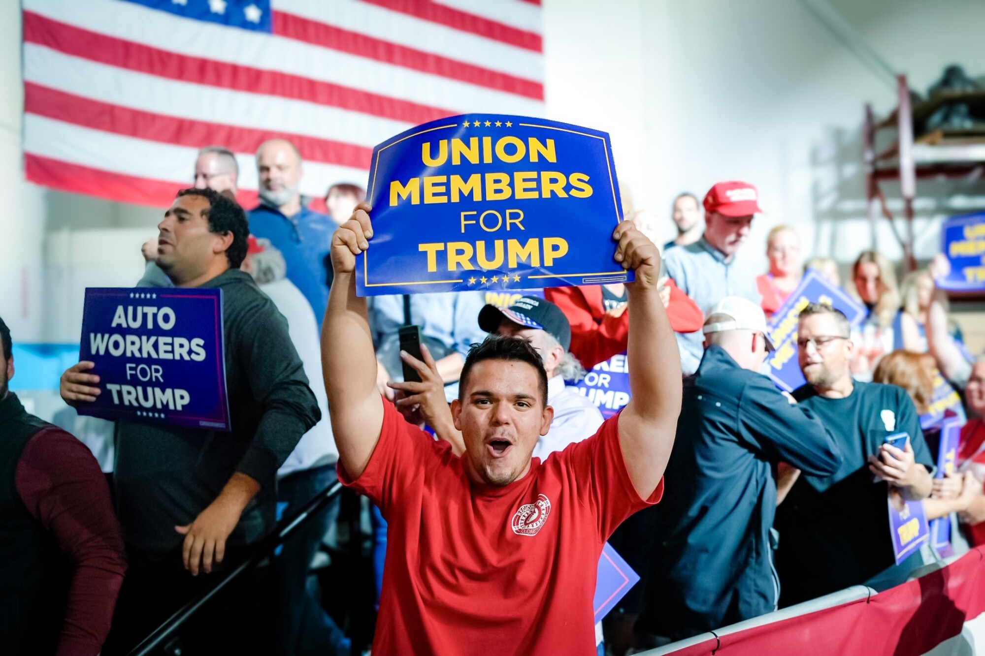 Isaiah Goddard, trabajador automovilístico de tercera generación, ondea una pancarta mientras espera a que el expresidente Donald Trump hable en un mitin electoral en Clinton Township, Míchigan, el 27 de septiembre de 2023. Goddard afirmó que los aranceles de Trump están reactivando la industria automovilística estadounidense y devolviendo los puestos de trabajo del sector manufacturero al país. (Cortesía de Isaiah Goddard).