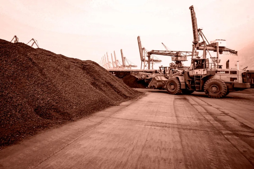 Un hombre conduce una pala cargadora para trasladar tierra que contiene minerales de tierras raras para su exportación a Japón en un puerto de Lianyungang, provincia de Jiangsu, China, el 5 de septiembre de 2010. (Editado por The Epoch Times, STR/AFP a través de Getty Images)