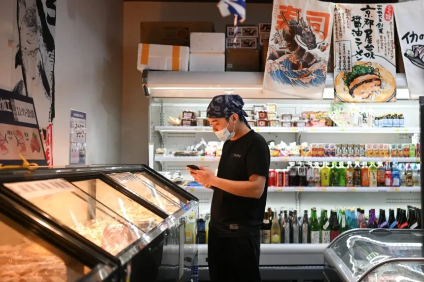Se observa a un trabajador en un supermercado de productos japoneses en Beijing el 19 de noviembre de 2025. (Pedro Pardo/AFP vía Getty Images)