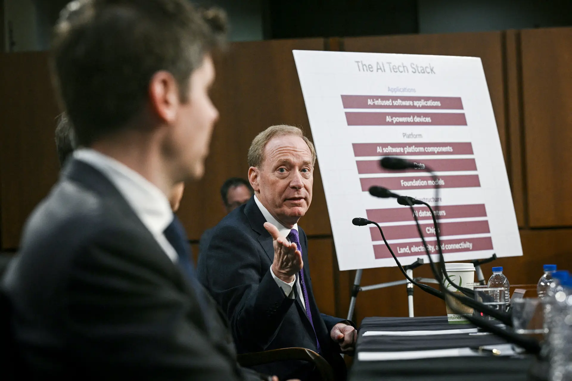 El vicepresidente y presidente de Microsoft, Brad Smith (derecha), y el director ejecutivo de Open AI, Sam Altman, hablan durante una audiencia del Comité de Comercio del Senado sobre inteligencia artificial en Washington el 8 de mayo de 2025. (Brendan Smialowski/AFP a través de Getty Images).