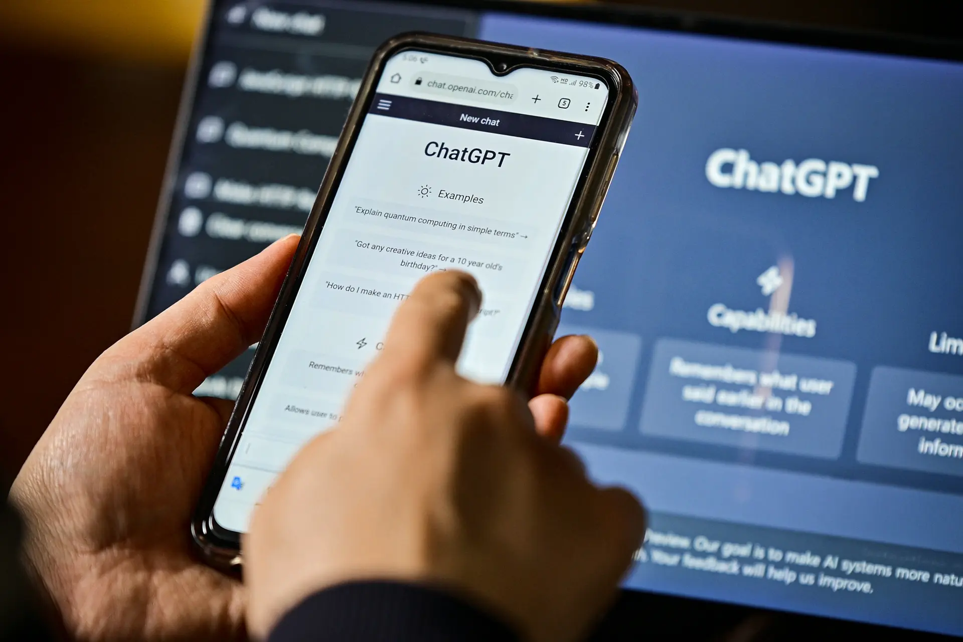 En esta fotografía de archivo, una pantalla de ordenador muestra el sitio web de ChatGPT y una persona utiliza ChatGPT en un teléfono móvil. (Ju Jae-young/Shutterstock).