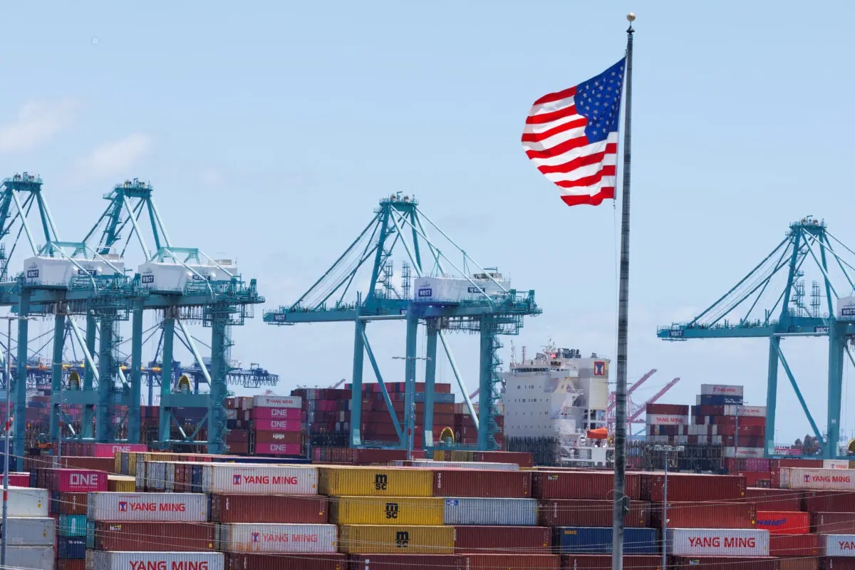 Una bandera estadounidense ondea sobre un barco y contenedores de transporte en el puerto de Los Ángeles, en San Pedro, California, el 13 de mayo de 2025. (Mike Blake/Reuters)