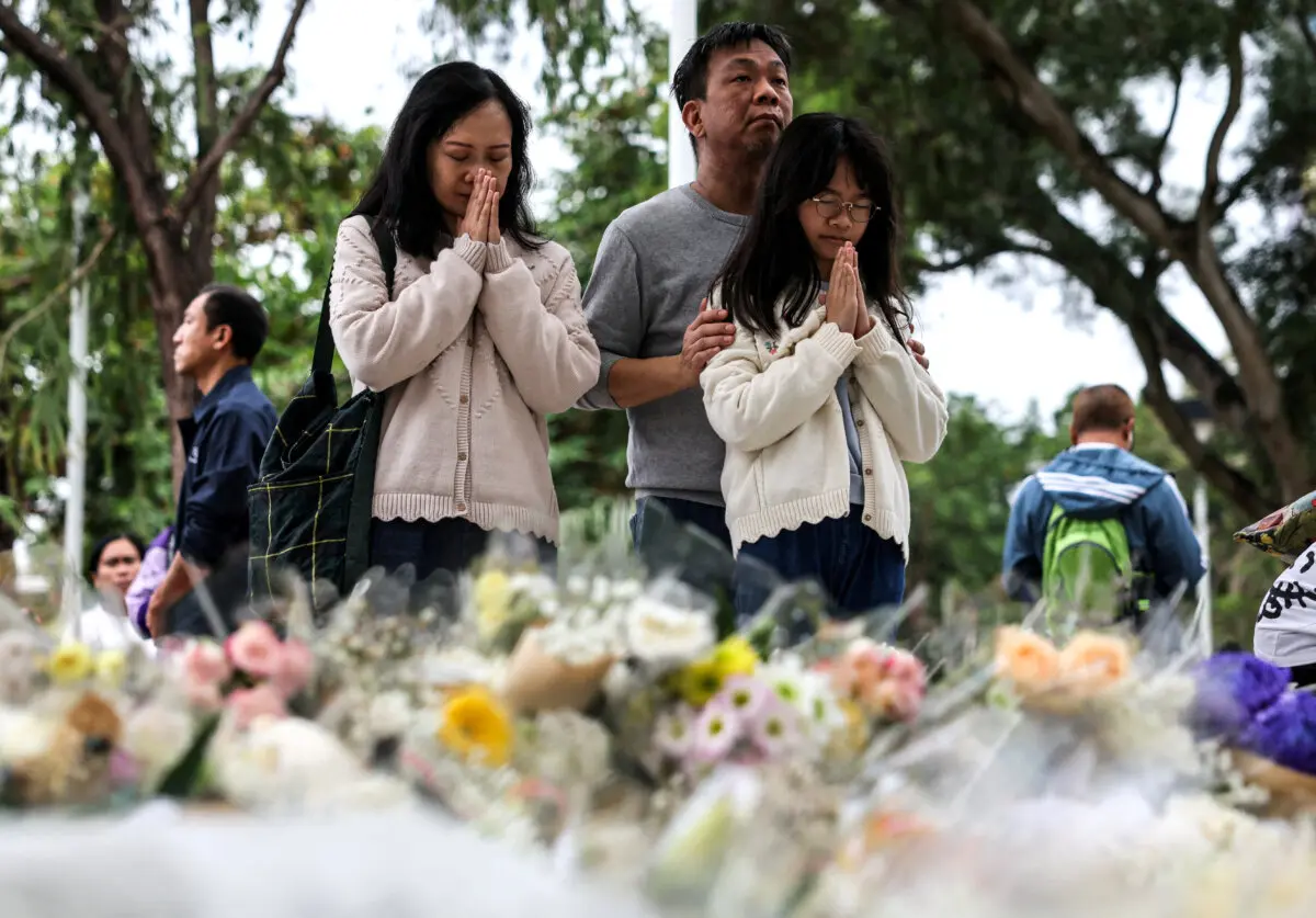 La gente reza mientras deposita flores en el memorial improvisado en honor a las víctimas del mortal incendio del complejo residencial Wang Fuk Court, en Tai Po, Hong Kong, el 30 de noviembre de 2025. Maxim (Shemetov/Reuters).