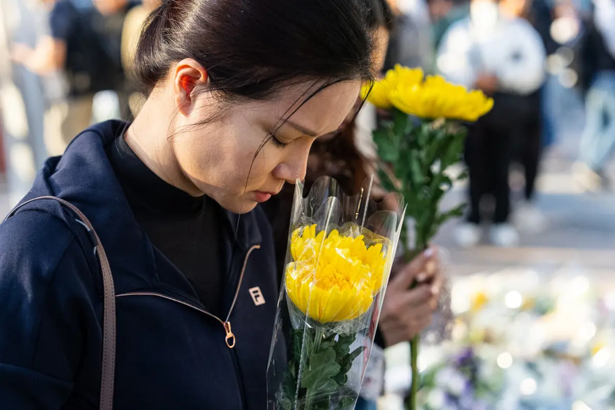 Las personas sostienen flores cerca del lugar para llorar a las víctimas del mortal incendio en Wang Fuk Court, una urbanización residencial en el distrito Tai Po de los Nuevos Territorios de Hong Kong, el 29 de noviembre de 2025. (Chan Long Hei/AP Photo).