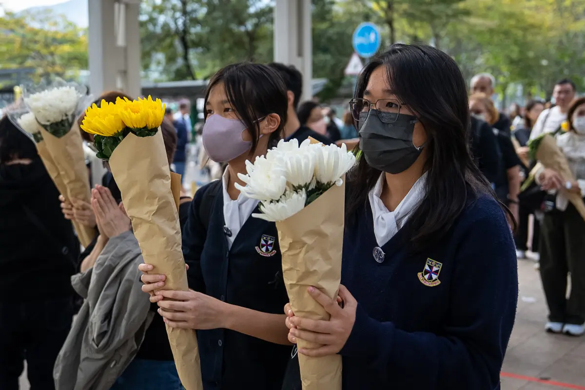 <em>La gente ofrece flores a las víctimas cerca del lugar del incendio mortal del miércoles en Wang Fuk Court, una urbanización en el distrito de Tai Po (Nuevos Territorios), Hong Kong, el 1 de diciembre de 2025. (Chan Long Hei/Foto AP)</em>