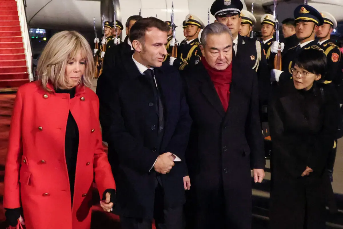 El ministro de Asuntos Exteriores de China, Wang Yi (segundo por la derecha), recibe al presidente de Francia, Emmanuel Macron (segundo por la izquierda), y a su esposa, Brigitte Macron (izquierda), a su llegada al Aeropuerto Internacional de la Capital, en Beijing, el 3 de diciembre de 2025. (Ludovic Marin/POOL/AFP a través de Getty Images).