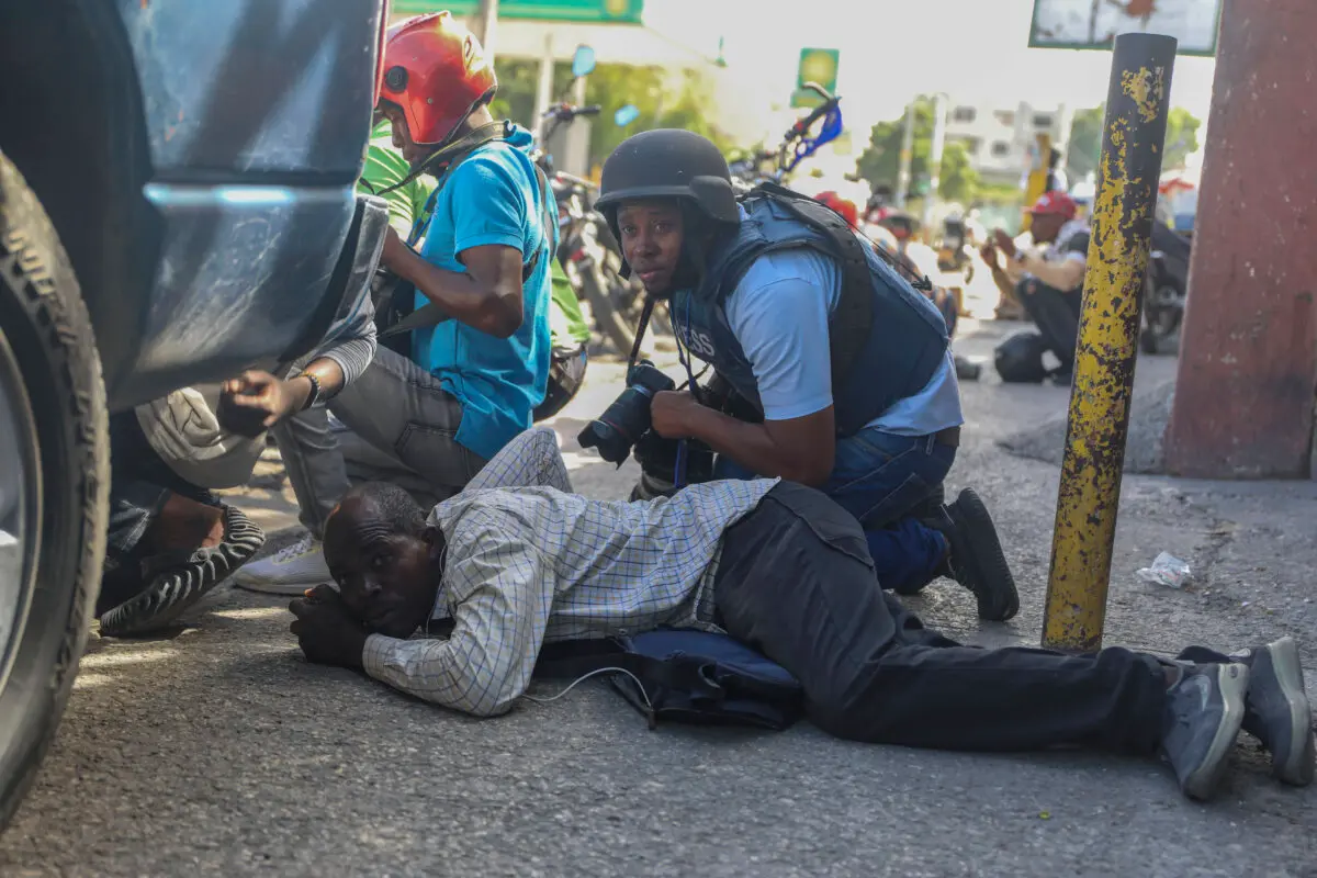 <em>Periodistas se refugian de un tiroteo entre miembros de pandillas y los policías en Puerto Príncipe, Haití, el 11 de noviembre de 2024. (Odelyn Joseph/AP Photo)</em>
