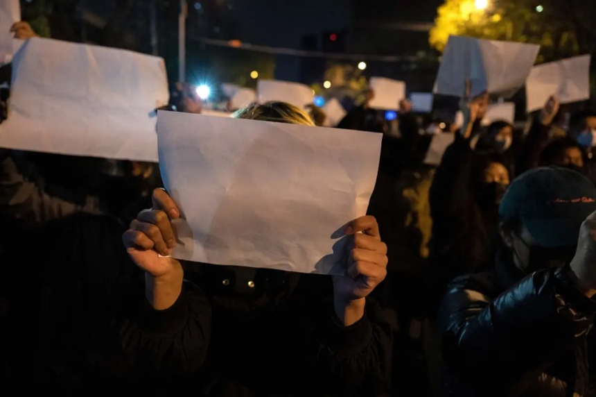 Manifestantes sostienen una hoja de papel en blanco contra la censura mientras marchan durante una protesta contra las estrictas medidas de COVID cero de China, en Beijing, el 27 de noviembre de 2022. (Kevin Frayer/Getty Images)